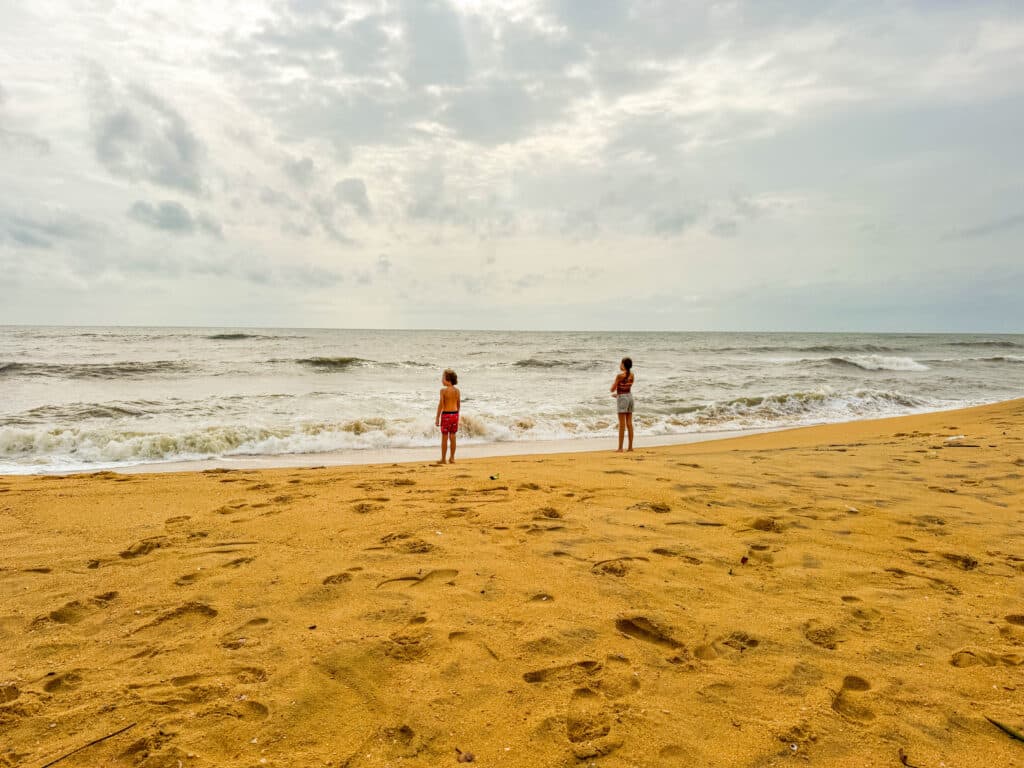 Les meilleures villes à visiter au Sri Lanka : un guide pratique des régions, itinéraires et points de chute 1 Des enfants debout au bord de l'eau sur la plage de Negombo, un littoral calme et spacieux souvent utilisé comme première étape lors d'une visite au Sri Lanka.