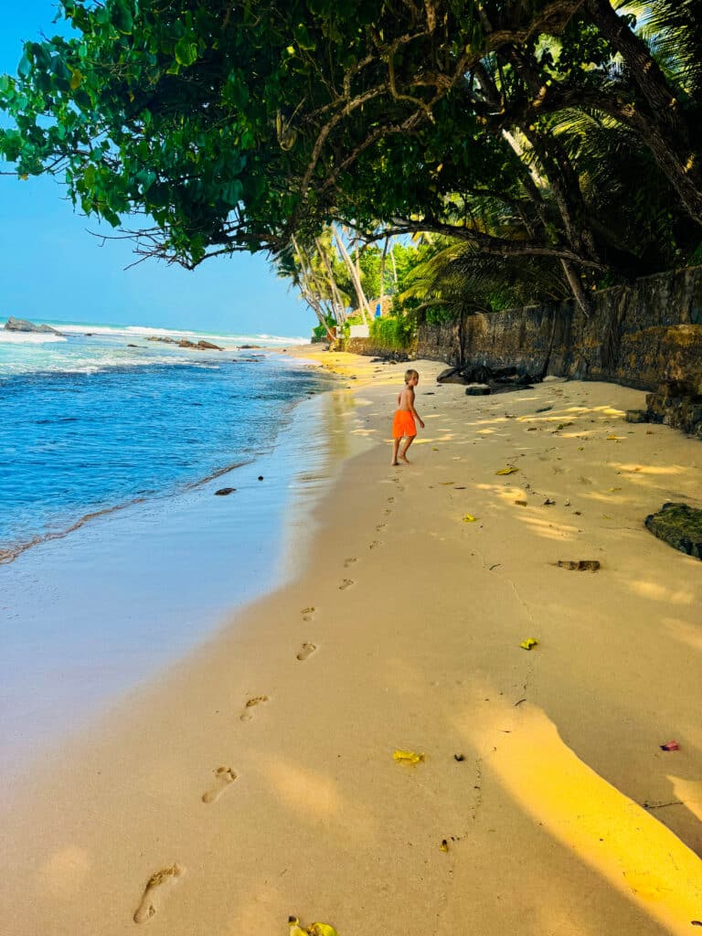 Les meilleures villes à visiter au Sri Lanka : un guide pratique des régions, itinéraires et points de chute 12 Enfant marchant le long du rivage de la plage d'Unawatuna, une baie calme et familiale sur la côte sud du Sri Lanka.