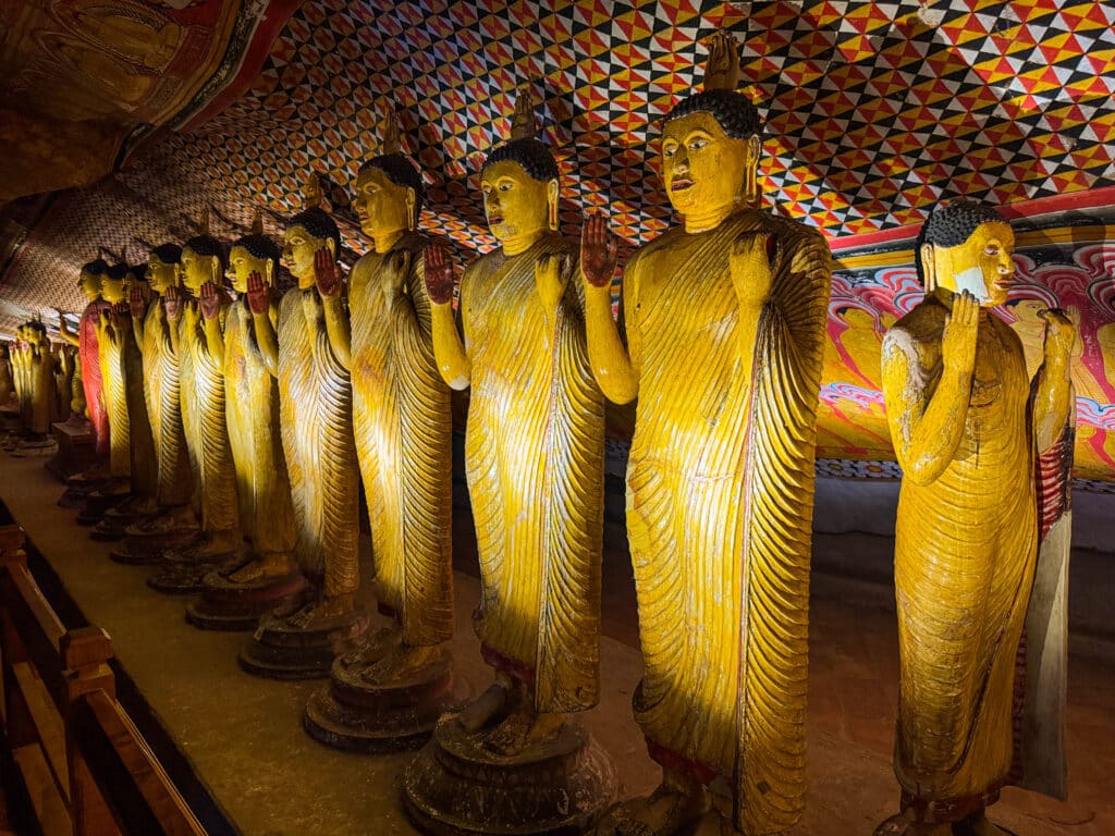 Golden Buddha statues inside the Dambulla Cave Temple with colorful painted ceilings in Sri Lanka