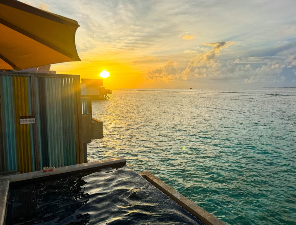 Golden sunset over the ocean seen from a private pool villa at Hard Rock Hotel Maldives.