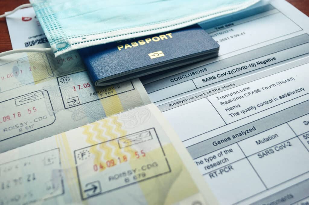 Passport, entry stamps and a negative Covid test laid out for safe international travel.