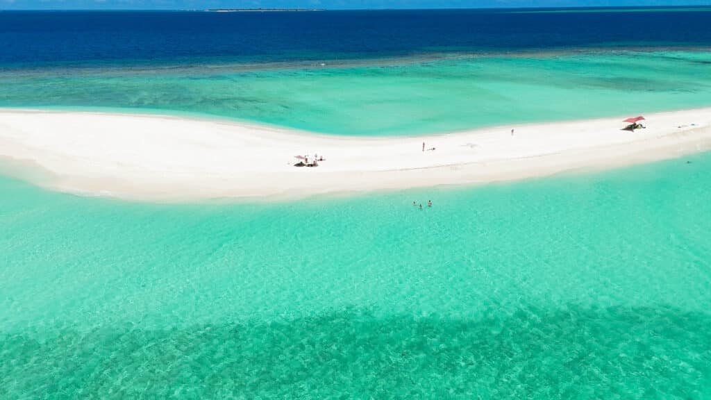 Long white sandbar surrounded by shallow turquoise sea where families enjoy a peaceful sandbank maldives day.