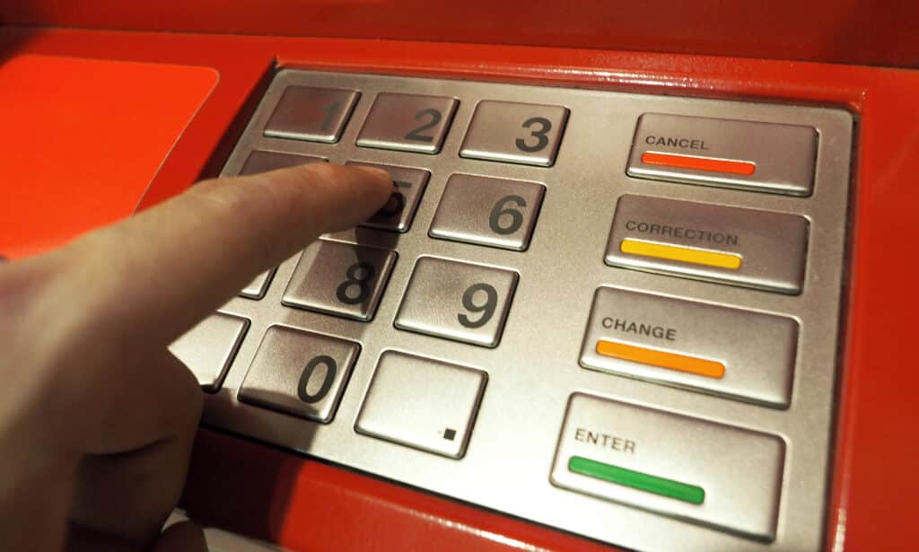 Hand entering a PIN at a Sri Lankan ATM to withdraw travel cash.