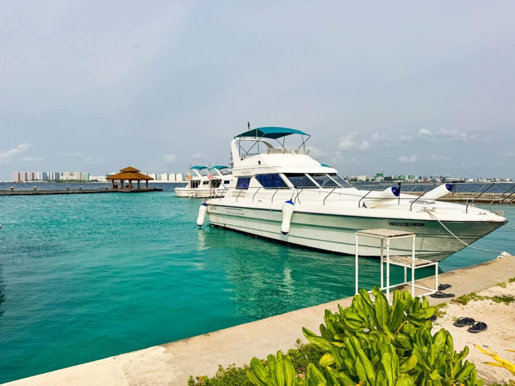 White speedboat moored at a Maldivian harbour with the skyline of Malé in the background.