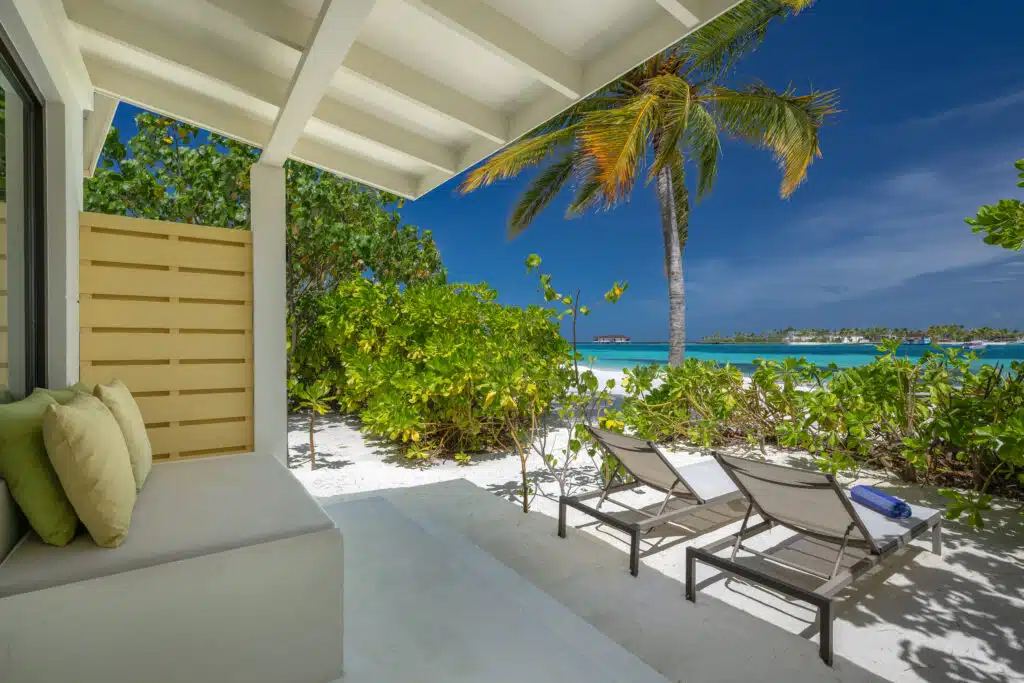Los mejores resorts económicos en Maldivas: 10 opciones asequibles 1 terraza de villa de playa con tumbonas y vistas a la laguna turquesa en un resort económico en Maldivas
