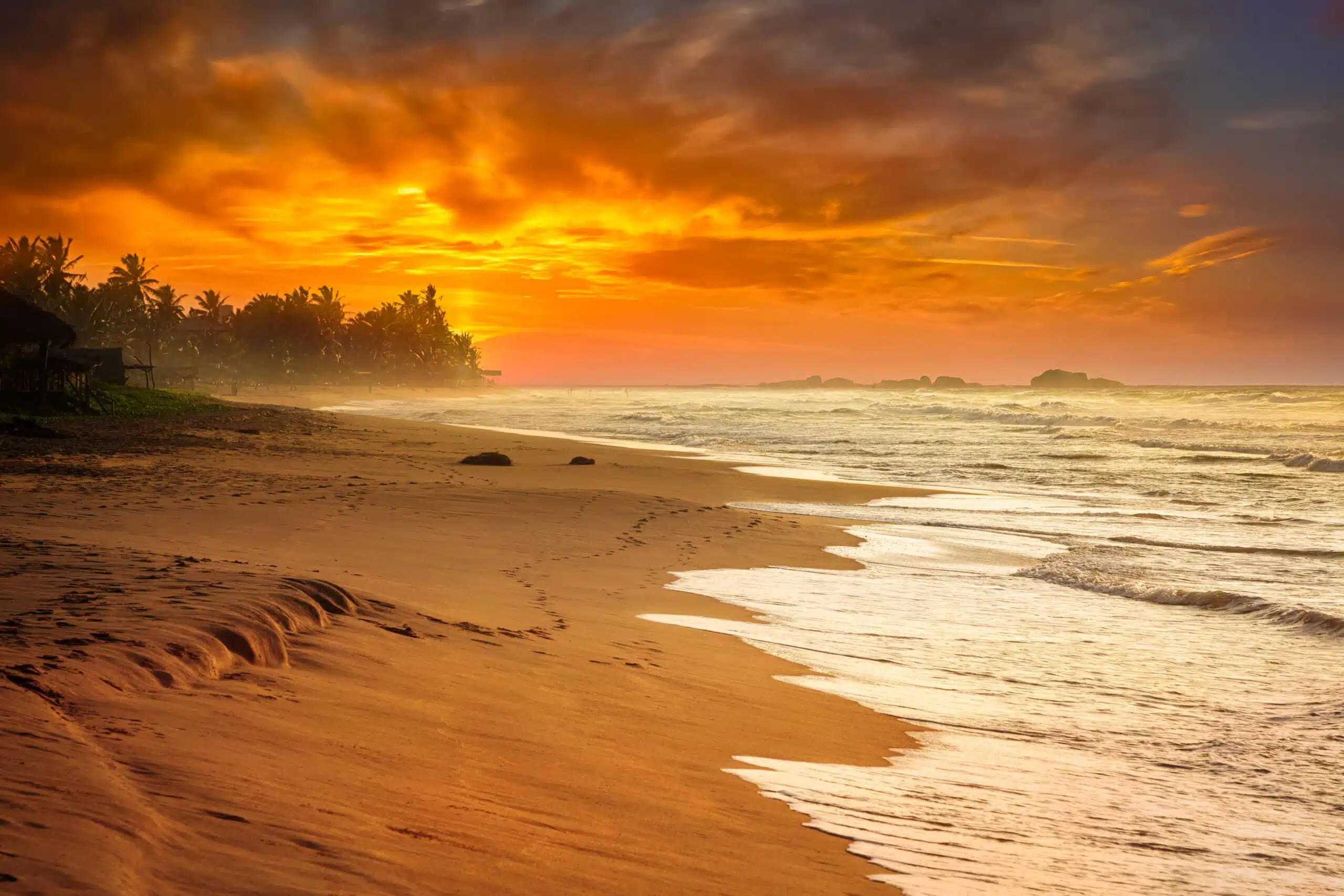 Gouden zonsondergang boven de golven op het strand aan de zuidkust van Sri Lanka.