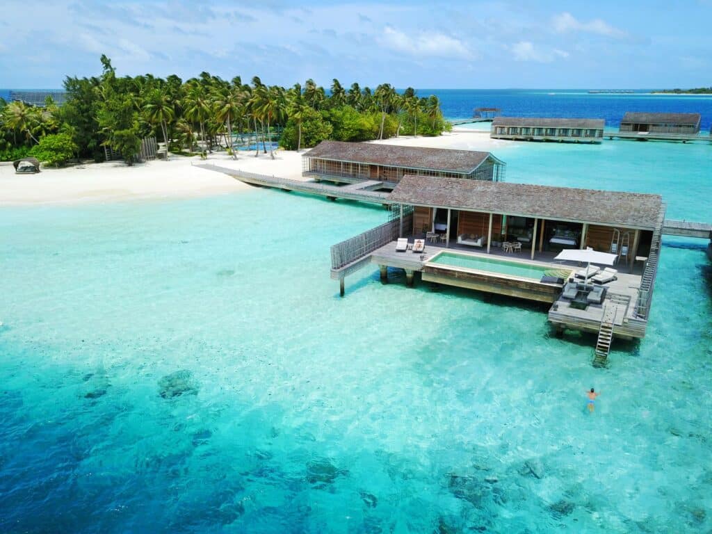 Luxury overwater villas with private pools stretch into a turquoise Maldivian lagoon.