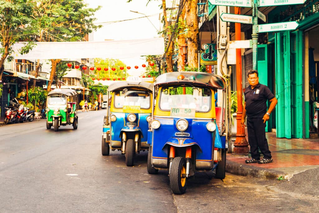 Colorful tuk‑tuks parked along a busy Asian street ready for passengers.