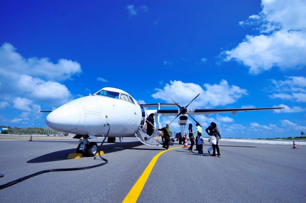 Passengers boarding a small aircraft on a sunny runway in the Maldives.