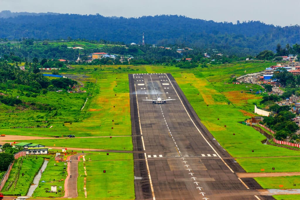 Airplane landing on a green runway at a Sri Lankan airport surrounded by villages.