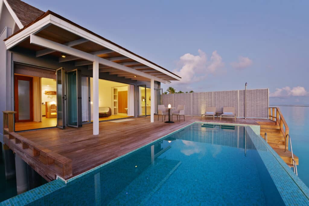 Luxury overwater villa with a private pool overlooking the calm Maldivian lagoon at dusk.