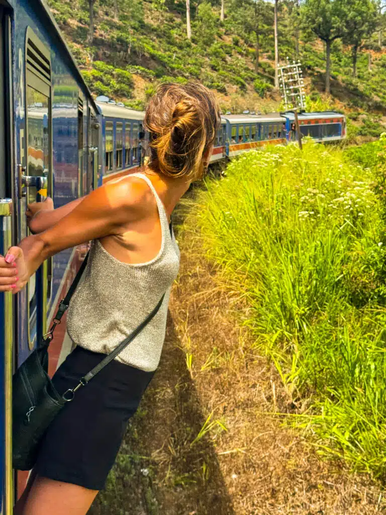 Le migliori cose da fare in Sri Lanka: le esperienze più gratificanti sull'isola 9 Donna che si sporge dalla porta aperta di un treno sulla panoramica ferrovia della regione collinare in Sri Lanka