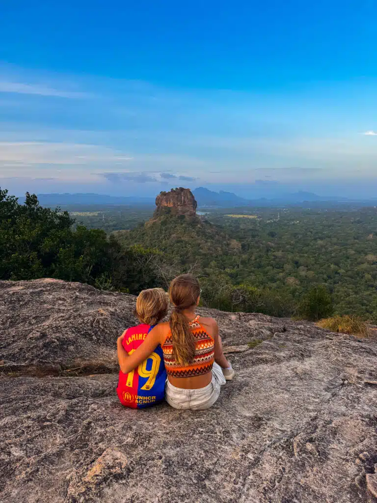 Le migliori cose da fare in Sri Lanka: le esperienze più gratificanti sull'isola 6 Due bambini seduti su Pidurangala Rock mentre guardano Sigiriya Lion Rock che si erge sopra la giungla: cosa fare nello Sri Lanka