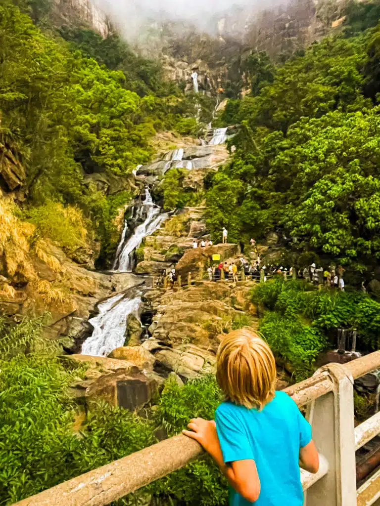 Le migliori cose da fare in Sri Lanka: le esperienze più gratificanti sull'isola 21 Bambino che guarda Ravana Falls che scende lungo le scogliere rocciose circondate dalla giungla vicino a Ella, Sri Lanka