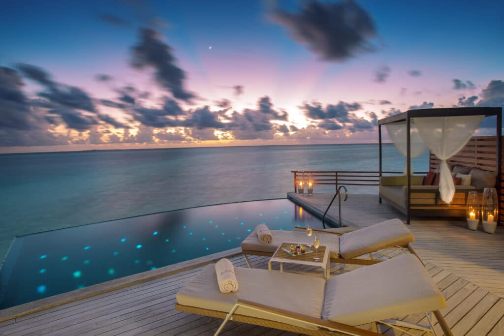 How to Choose a Maldives Resort: The Complete Decision Guide 4 overwater pool villa deck at Baros Maldives at sunset with infinity pool candles and dramatic sky