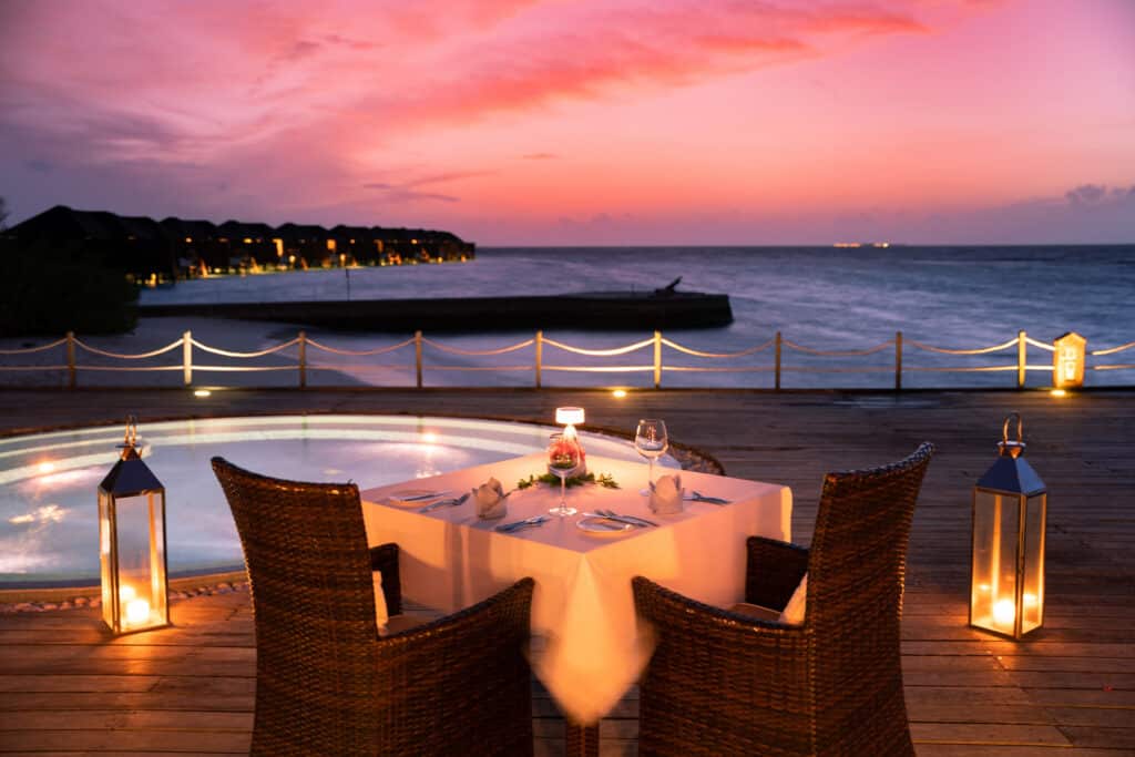 Los mejores resorts de Maldivas con mejor relación calidad-precio: 10 islas privadas que superan su precio 12 mesa romántica con cena a la luz de las velas al atardecer en una terraza de madera en Lily Beach Resort Maldives