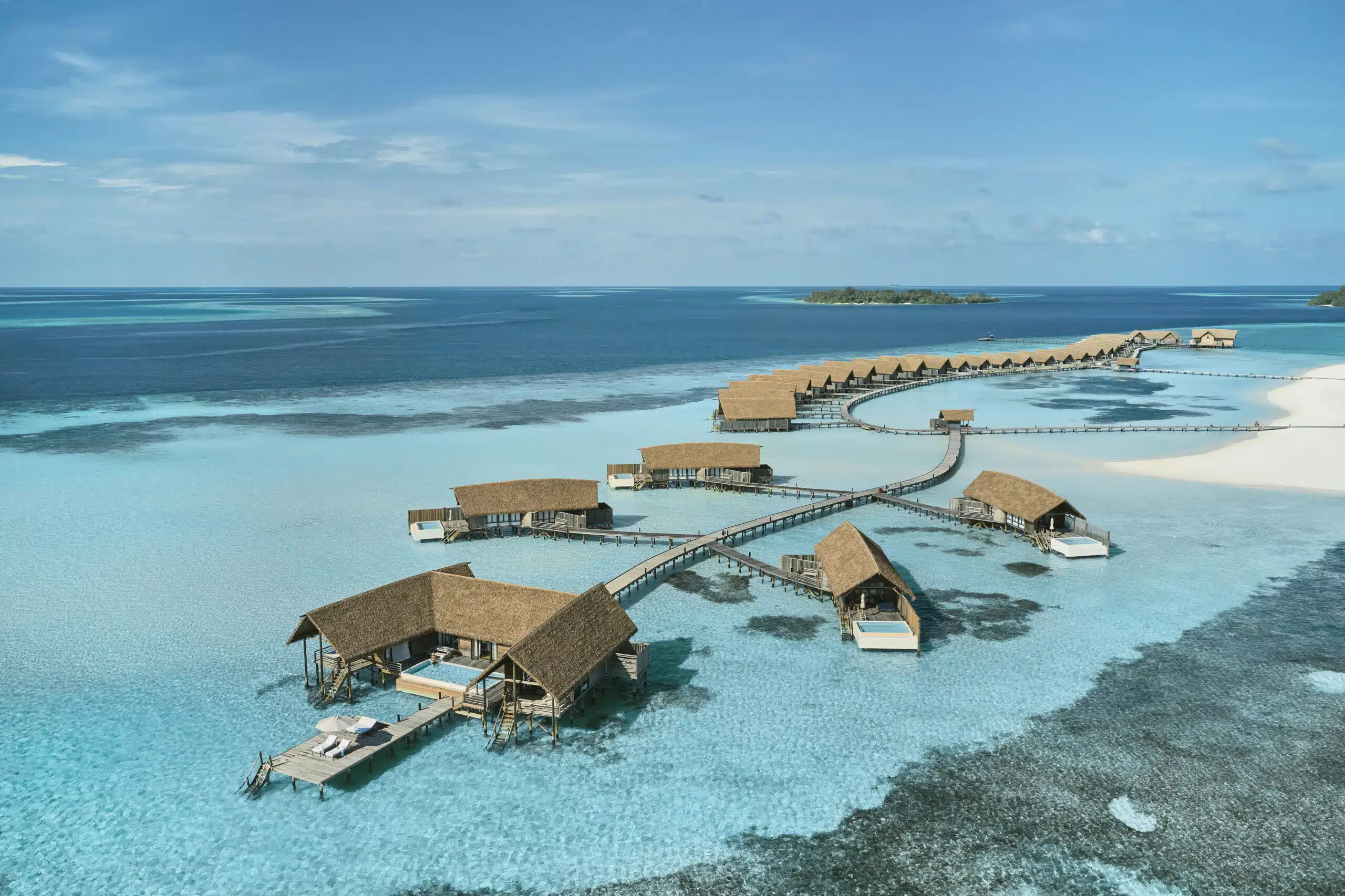 Come scegliere un resort alle Maldive: la guida decisionale completa 33 vista aerea delle ville sull'acqua di Como Cocoa Island Maldives sopra una laguna con barriera corallina turchese