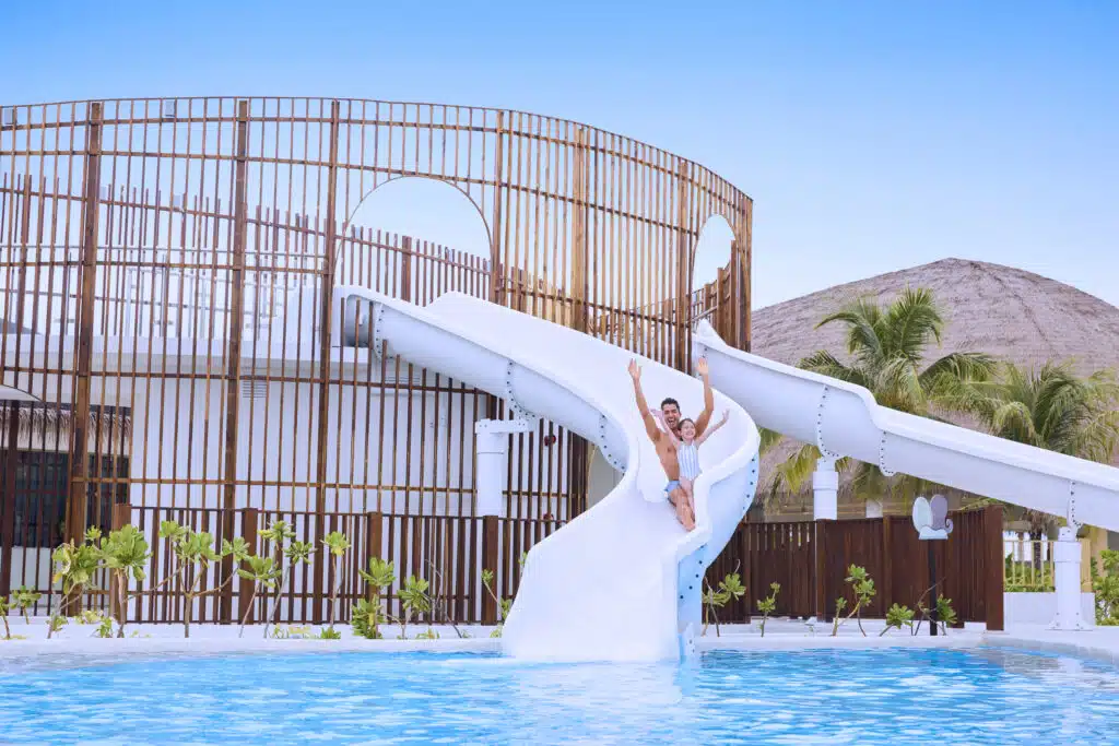 I migliori resort alle Maldive vicino a Malé: 10 isole top vicine all'aeroporto 9 padre e figlio che scivolano giù da uno scivolo d'acqua bianco in una piscina con le braccia alzate