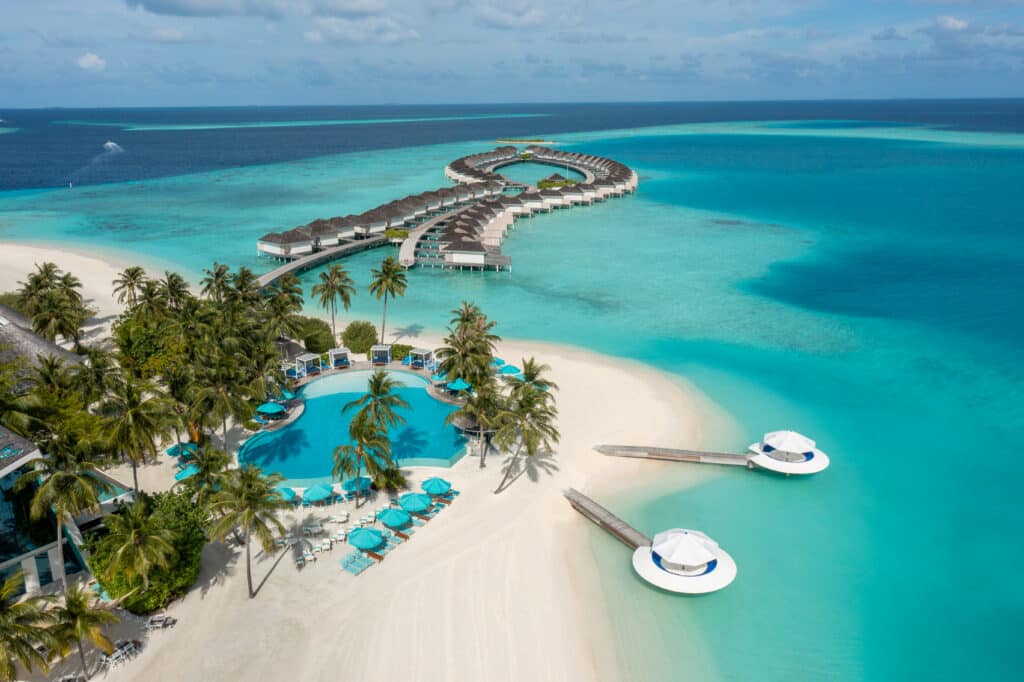 I migliori resort alle Maldive per chi visita per la prima volta: 10 isole che rendono tutto più semplice 9 vista aerea di Kandima Maldives con il pontile curvo delle ville sull'acqua, la piscina principale e la laguna turchese