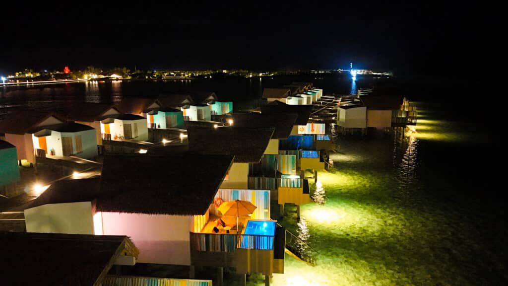 vista aerea notturna delle colorate ville sull'acqua illuminate all'Hard Rock Hotel Maldives
