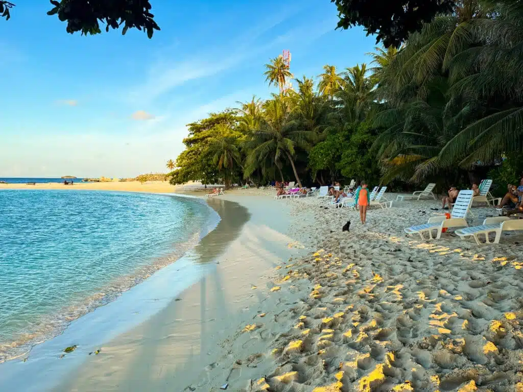 Isole locali delle Maldive vs Resort: cosa dovresti scegliere? 6 turisti che si rilassano sui lettini della bikini beach sull'isola locale di Dharavandhoo alle Maldive al tramonto