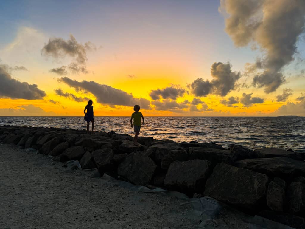 Maldive con bambini: resort o isole locali — Qual è la scelta giusta per la tua famiglia? 31 Famiglia che esplora la strada di un'isola locale maldiviana fiancheggiata da case colorate