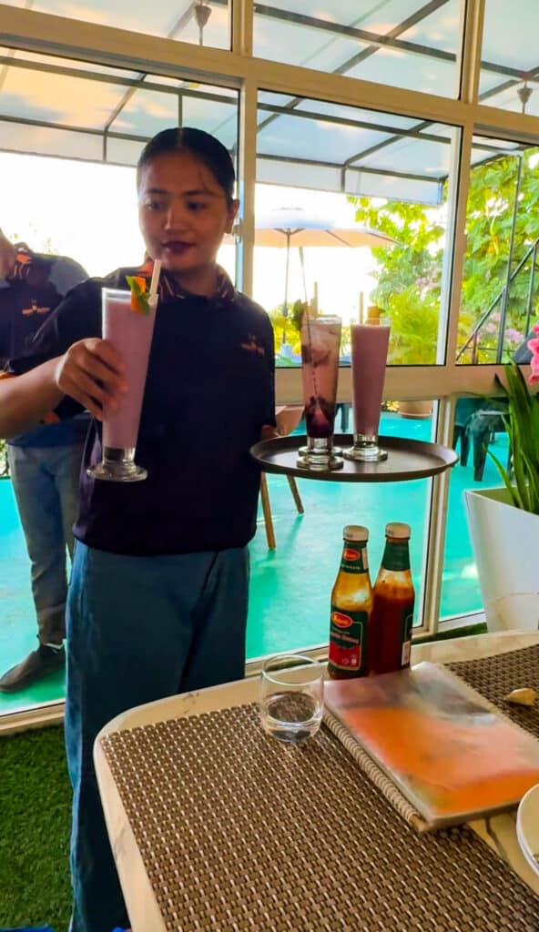 Isole locali delle Maldive vs Resort: cosa dovresti scegliere? 9 cameriera che serve frullati di frutta fresca in un bar di un'isola locale alle Maldive