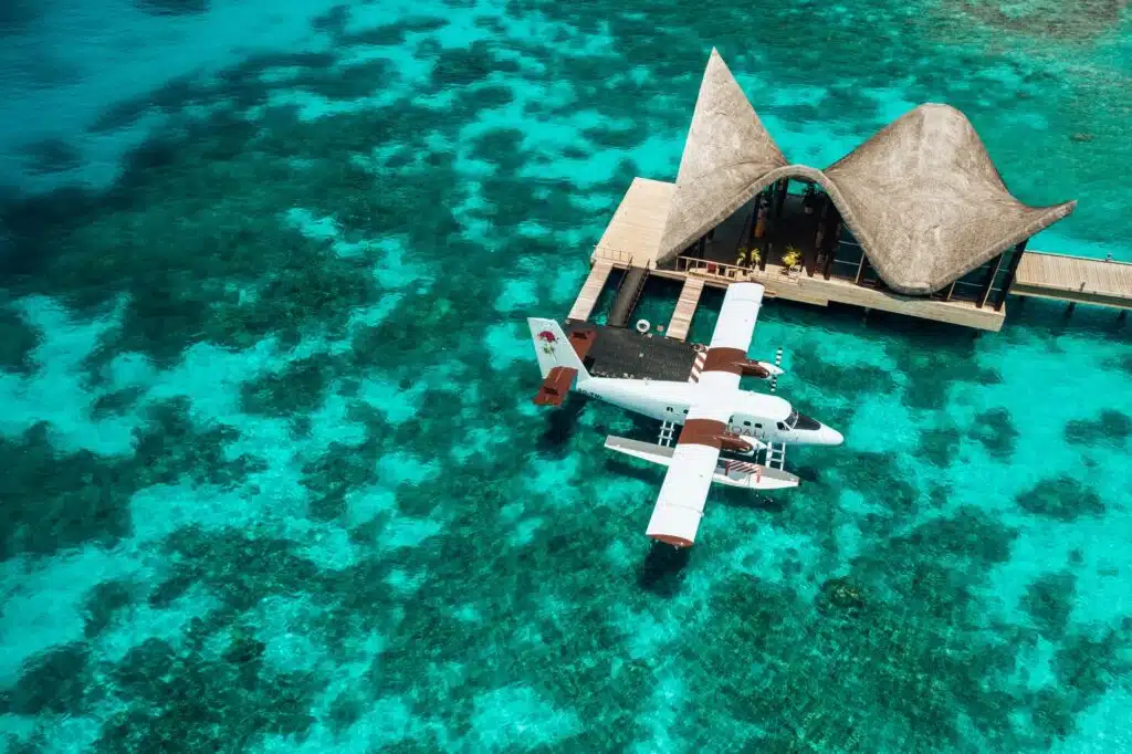 Isole locali delle Maldive vs Resort: cosa dovresti scegliere? 13 idrovolante attraccato al pontile di arrivo sull'acqua presso il resort Joali Maldives sopra una barriera corallina turchese