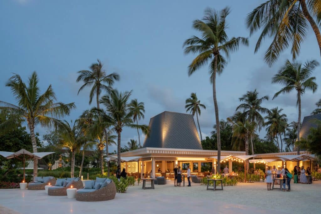 I migliori resort alle Maldive per chi visita per la prima volta: 10 isole che rendono tutto più semplice 17 ristorante all'aperto al Kuda Villingili Resort Maldives al crepuscolo con ospiti che cenano sotto le palme e le luci a festone