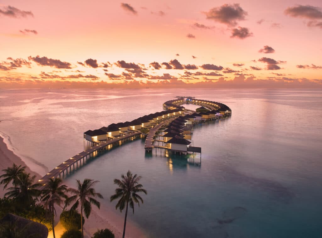Los mejores resorts de Maldivas con mejor relación calidad-precio: 10 islas privadas que superan su precio 15 vista aérea al atardecer del embarcadero de villas sobre el agua de Kandima Maldives curvándose sobre el tranquilo océano rosado