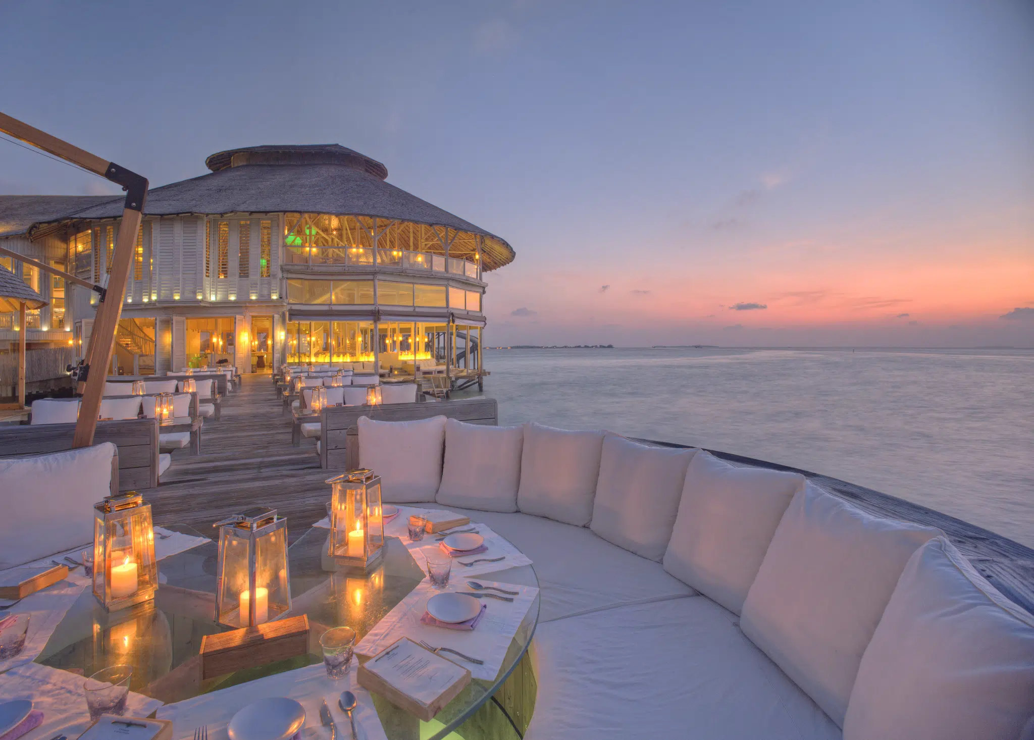 Isole locali delle Maldive vs Resort: cosa dovresti scegliere? 3 ristorante sull'acqua con tavoli a lume di candela e vista sull'oceano al Soneva Jani Maldives al tramonto