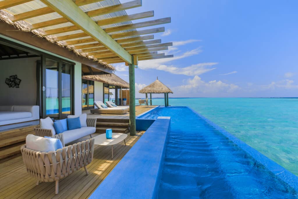 terrazza di una villa sull'acqua con piscina a sfioro e vista sulla laguna turchese al resort Velassaru Maldives