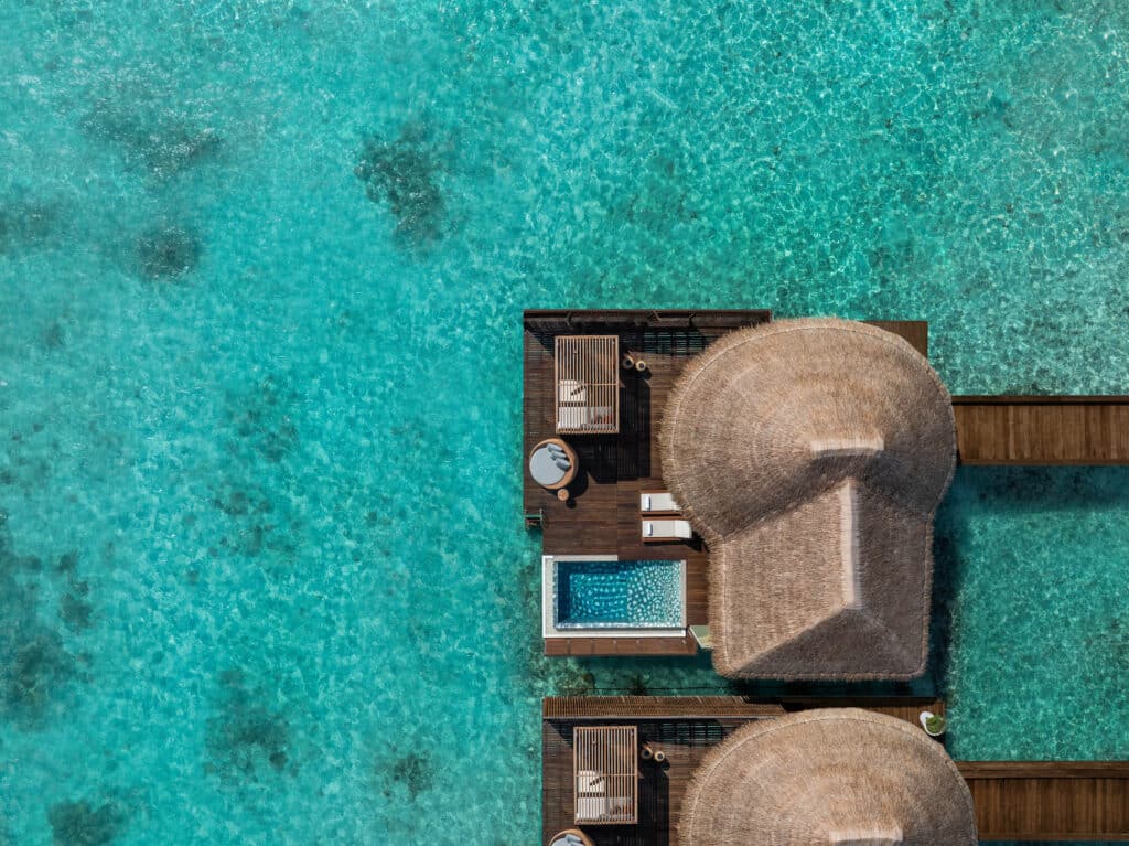 aerial view of overwater villa with private pool at W Maldives over turquoise reef lagoon