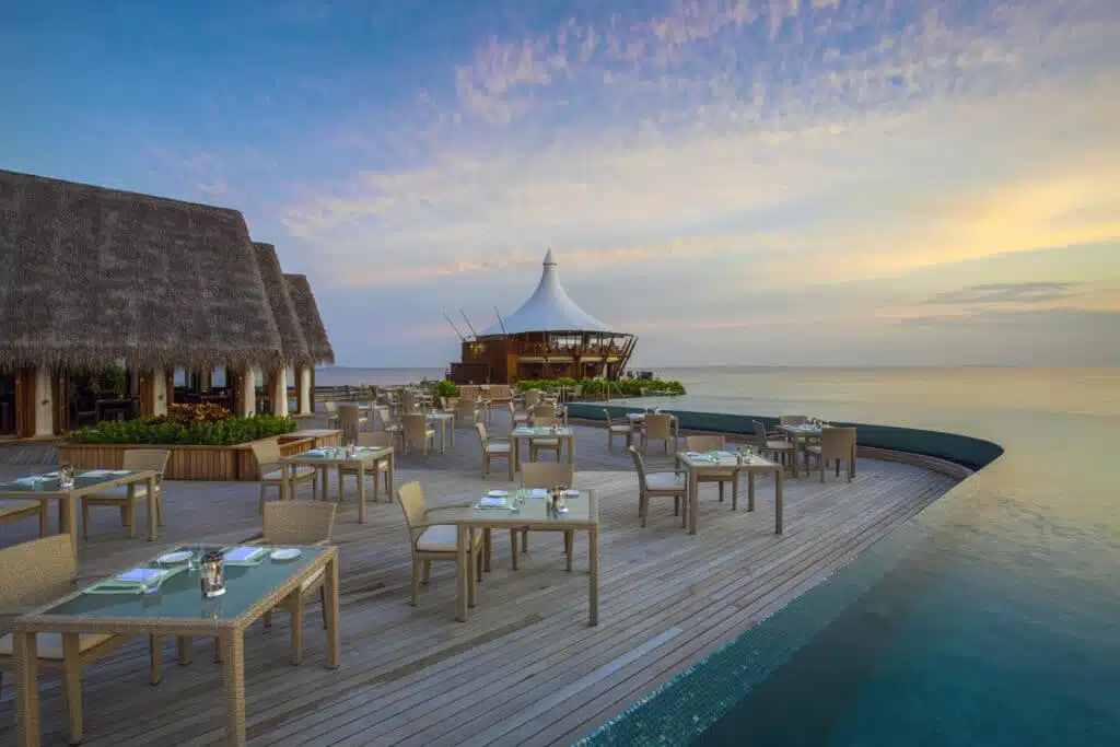 Isole locali delle Maldive vs Resort: cosa dovresti scegliere? 1 terrazza del ristorante sull'acqua al tramonto presso il resort Baros Maldives con vista sull'oceano