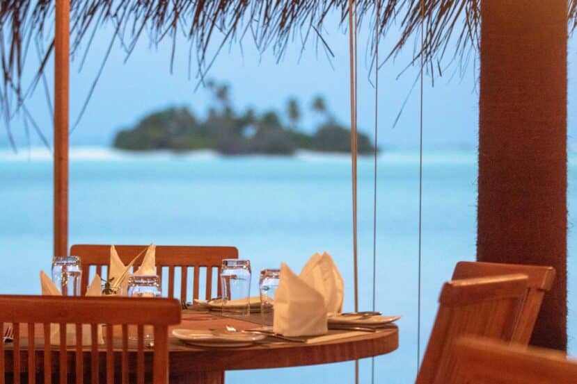 Ukulhas Maldives: The Best Local Island for Snorkelling, Clean Beaches & Island Life 10 restaurant table and chairs under a shaded terrace looking out over turquoise water to a small island
