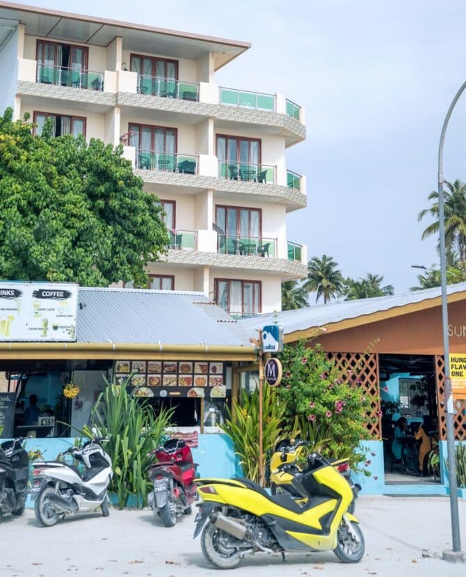 Thulusdhoo Maldives: The Best Local Island for Surfing, Budget Stays & Easy Island Life 10 local street with small shops, signage and parked scooters on Thulusdhoo