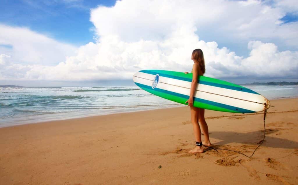 Sri Lanka South Coast: Beaches, Surf Towns & Coastal Travel 12 woman carrying a colourful surfboard at a beach in Weligama ready for surf lessons